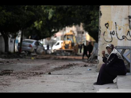 Credit: AP A woman sits near the site where three Palestinians were killed by Israeli fire.