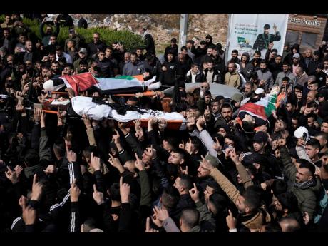 Credit: AP Palestinian mourners carry the bodies of three men during their funeral in the West Bank town of Tubas.