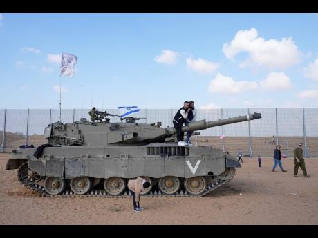 Credit: AP Israelis stand on tanks during an event for families of reservists outside a military base in southern Israel.
