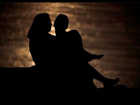 FILE - In this June 27, 2018 file photo, a couple is silhouetted against moonlight reflecting off the Missouri River as they watch the full moon rise beyond downtown buildings in Kansas City, Mo. Money can create stress within a relationship, but talking through expectations and money beliefs can help couples get on the same page. In fact, conflict over money can be healthy, partly because we often partner with people who are our financial opposites.