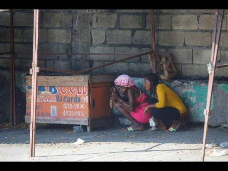 Women take cover during a gun battle between police and gang members in Port-au-Prince, Haiti,  last Friday. 