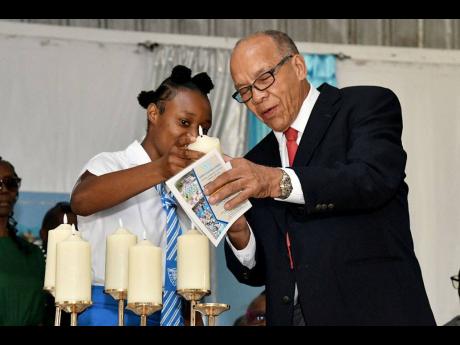 Edwin Allen High’s head girl, Monique Stewart, assists past student Everton Roache to light a candle during the school’s 60th anniversary thanksgiving service at the institution in Clarendon in January.