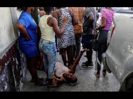 A woman lies on the pavement as she mourns a family member shot dead by unknown assailants as he sat on his motorcycle in the Delmas area of Port-au-Prince, Haiti, Friday, on March 8. AP 