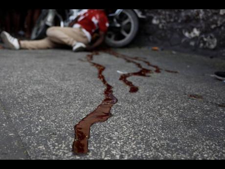 The body of a man lies in a pool of blood alongside his motorcycle, in the Delmas area of Port-au-Prince, Haiti, on March 8. 