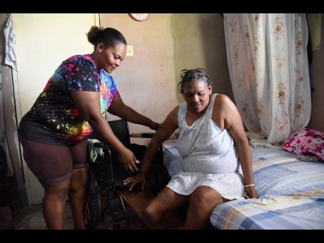 Petresa Reece assists her mother Maxine Hyatt from her bed to a wheelchair. 