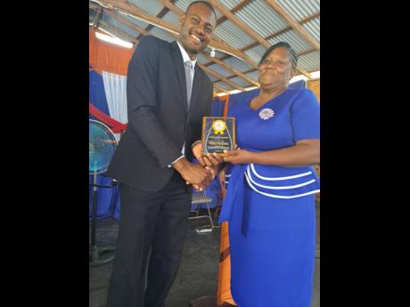 Principal of the Rosehall Basic School, Maureen Brown, getting her award for 22 years of service from Pastor Sean Williams.
