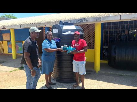 Sean Greenfield (left), director of the Negril Entertainment Association (NEA), looking on while Patrice Phrame (centre), vice-principal of Negril Primary School, accepts a water pump and water tank from NEA member Livingston Rose at the school on Wednesday.