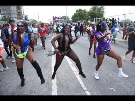 Expressing their enjoyment through dance while marching with the Xodus band are (from left) Monique Lee-Sin, Devonae Mason and Kerry-Ann Morrison.