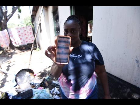 Trecia Ellis, the owner of the house where six firefighters were injured yesterday while putting out a blaze, shows her electricity bills on her smartphone.