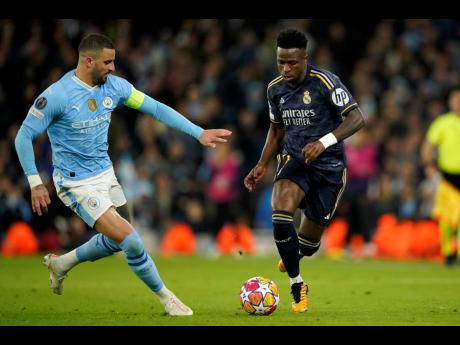 Manchester City’s Kyle Walker (left) fights for the ball with Real Madrid’s Vinicius Junior during their Champions League quarter-final second-leg football match at the Etihad Stadium in Manchester, England, yesterday. Madrid won 4-3 on penalties after a 4-4 aggregate draw.