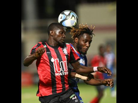 Rushane Thompson (left) of Arnett Gardens battles with Portmore United’s Akeem Mullings during Monday  night’s Jamaica Premier League playoff game at Sabina Park. The game ended in a 1-1 draw.