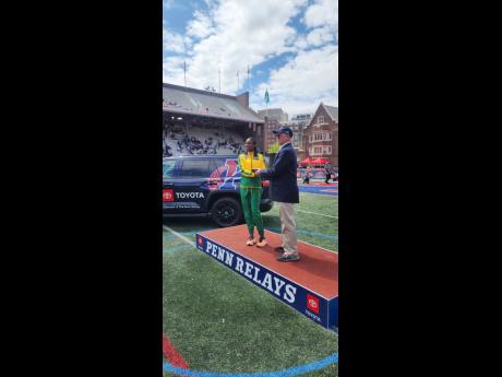 St  Jago High’s Jade-Ann Dawkins (left) collects a Penn Relays commemorative watch on Thursday for winning the high school girls’ Championships of America triple jump with 13.01 metres to defend her title.
