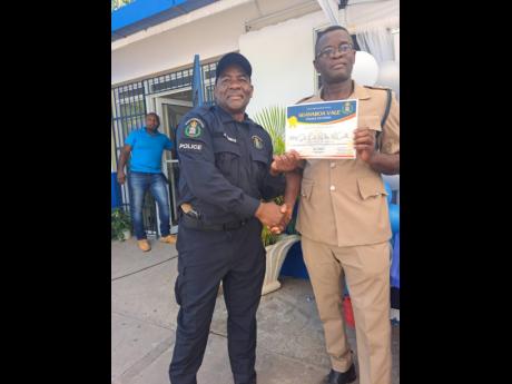 Deputy Superintendent of Police Fitz-Albert Linton (right) presents District Constable Ralston McCalla with a certificate of appreciation for his work in the St Catherine North Division. Lawmen in the division were recognised for their work as part of the Police Social Action Day which was held at the Guanaboa Vale Police Station.