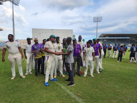 Kingston Cricket Club’s captain Akim Fraser (foreground left) and coach Terrence Corke enjoy the limelight of holding the JCA Senior Cup while other players and officials watch after the final at Sabina Park yesterday.