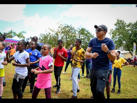 Minister of Health and Wellness, Dr Christopher Tufton, goes through several exercise routines with students participating in last Friday’s National School Moves Day event at Manchester High School, in Mandeville. 