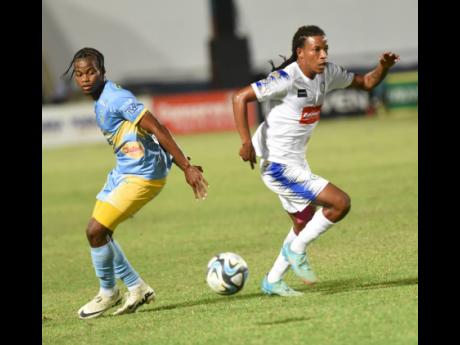 Mount Pleasant’s Kimoni Bailey (right) goes by Waterhouse’s Navardo Blair during their first-leg semi-final match in the Wray and Nephew-sponsored Jamaica Premier League at Sabina Park yesterday. The game drew 1-1.