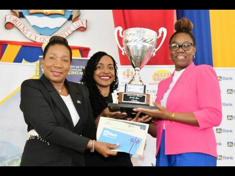 State Minister in the Ministry of Education and Youth, Marsha Smith (centre), presents the 2024 Mathematics Teacher of the Year trophy to Cameka Ingram (right) of Green Pond Primary and Infant School in St James, at the awards ceremony held recently at the University of the West Indies, Mona campus.  Sharing the moment is Manager, Public Sector Engagement at Jamaica National Bank, Sandra Jones.
