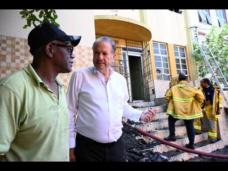 Tom Tavares-Finson (right), president of the Senate, chat with fellow attorney Wentworth Charles in the fire’s aftermath.