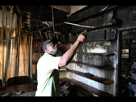 Wentworth Charles examines the damage to his office which was gutted by fire.