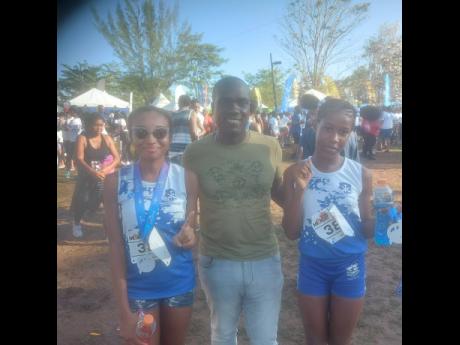 Winner and runner-up in the 5K category of the Jill Stewart MoBay City Run Karma Lewin (right) and Chris-Ann Edwards  celebrate with coach Andrew Henry last Sunday at the Old Hospital Car Park in Montego Bay.