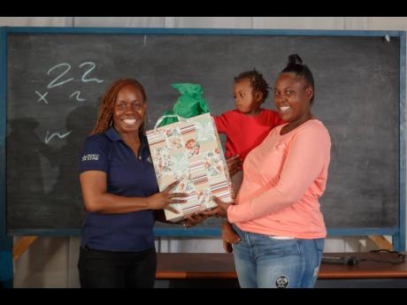 Karen McGlashin (left), social worker at Project STAR, presents Shanakay Powell with a gift at a parent club session recently.