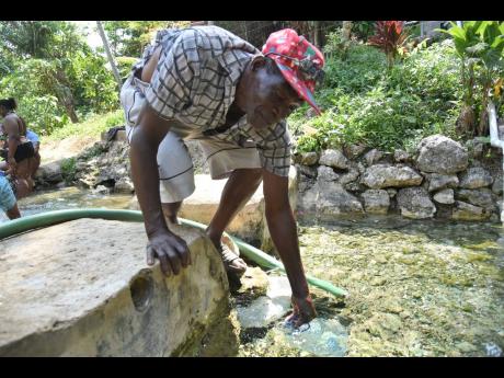 Carlton Thompson, resident of Springvale, St Catherine, fills a bottle with water.