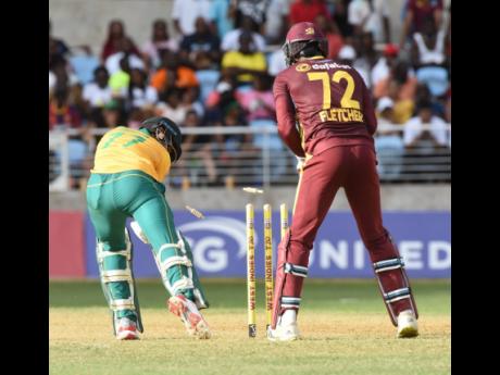 Bjorn Fortuin (left) of South Africa is bowled for zero by West Indies spinner Gudakesh Motie during the first T20 International match at Sabina Park yesterday.  The wicketkeeper is Andre Fletcher. 