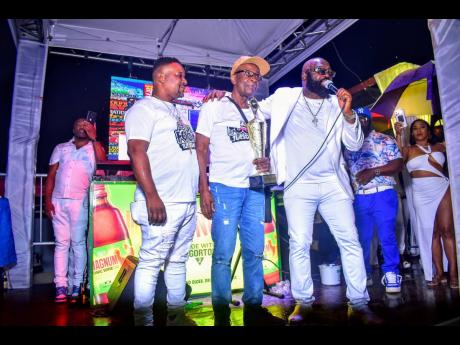 DJ Alanza Hawk (centre) accepts an award for long service to dancehall music. At left is Fabian 'Boomas' Cole, while singer Richie Stephens hails the general.