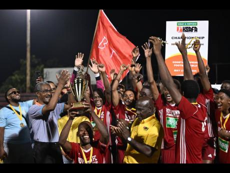 Boys’ Town’s players  celebrating with the KSAFA Championship League trophy after defeating the Jamaica Defence Force 6-5 on penalties at the Anthony Spaulding Sports Complex last night.  