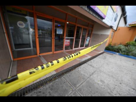 Credit: Ricardo Makyn Police cordon off the crime scene at a MoneyGram outlet in Portmore, St Catherine, which was robbed yesterday.