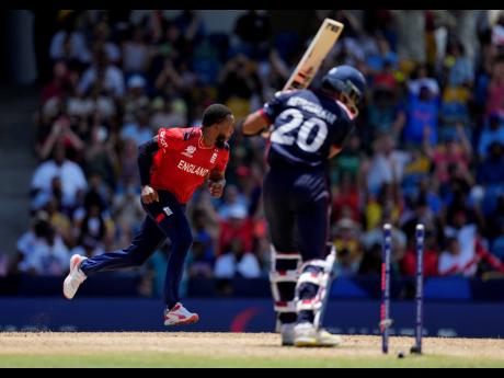 England’s Chris Jordan (left) celebrates after getting a hat-trick by dismissing United States’ Saurabh Nethralvakar (right) during the ICC Men’s T20 World Cup cricket match between the United States and England at Kensington Oval in Bridgetown, Barbados, yesterday.