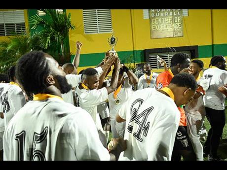 Chapelton Maroons celebrate  with the championship trophy after their win over Racers United in the Jamaica Football Championships (Tier II) final at the UWI-JFF Captain Horace Burrell Centre Of Excellence last night.