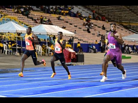 Kishane Thompson (right) takes a look at the clock as he stormed to a personal best of 9.82 seconds  to win his heat of the men’s  100 metres on day one of the JAAA/Puma National Junior and Senior Championships  at the National Stadium last night. 