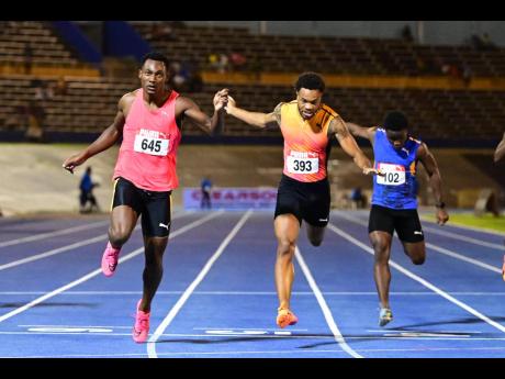 Bryan Levell (left) gets to the line ahead of defending national champion Andrew Hudson (centre) in the men’s 200m final at the JAAA/Puma National Junior and Senior Championships yesterday. Levell won in 19.97 seconds while Hudson was second in 20.02. 