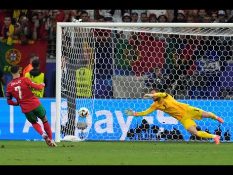 Portugal’s Cristiano Ronaldo (left)  scores past Slovenia’s Jan Oblak during the penalty shootout in the round-of-16 Euro 24 match in  Frankfurt, Germany, yesterday. 