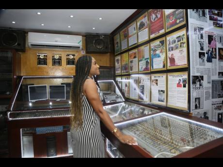 Blair Milan, host and creator of itiswhatitisja, reads the information on display at the Bunny Lee Museum.