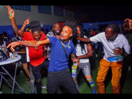 Dancehall artiste Willfullskilfull (centre) is cheered on by fellow dancehall artiste Chi Chi Ching (right) and others. 