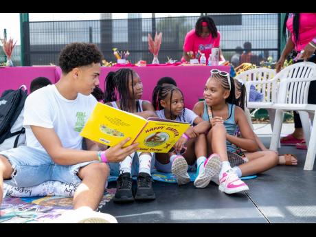 Joey Bogdanovich (left) reads the book ‘Curious George’ to the children at the Kiwanis Reading Corner.