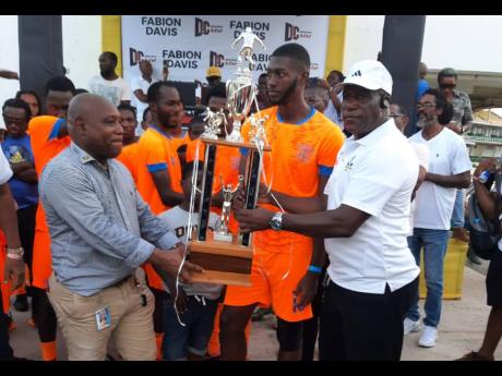 Councillor Fabian Davis (left) presenting the Trelawny Football Association (TFA) Major League title to Desmond Simpson, an executive member of the Duncans FA.