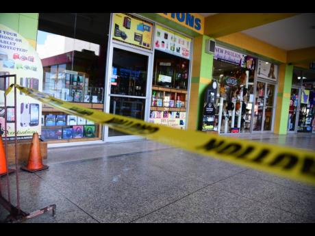 Police cordon off the area in which two women were attacked by men armed with acid in a mall in Half-Way Tree, St Andrew, yesterday.