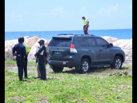 Police personnel process a crime scene on the Palisadoes road in Kingston where a soldier is believed to have committed suicide.