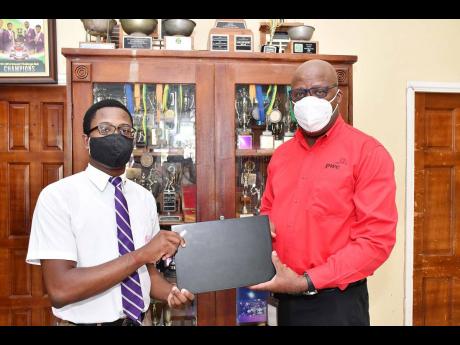 File photo shows Leighton McKnight (right) presenting one of two laptops donated by PwC Jamaica to Kingston College student Andrew Campbell during the David ‘Wagga’ Hunt Foundation presentation ceremony in 2022.