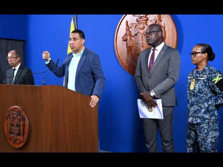 Prime Minister Andrew Holness (second left) speaks to the media on the latest in the investigation of the Clarendon massacre during a press conference yesterday at Jamaica House. Looking on are (from left) Deputy Prime Minister and Minister of National Security Dr Horace Chang, Deputy Commissioner of Police Fitz Bailey, and Chief of Defence Staff, Vice Admiral Antonette Wemyss Gorman.