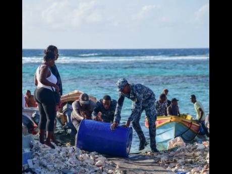 Credit: Antoine Lodge A resident of Pedro Cays assists members of the Jamaica Defence Force Coast Guard to offload potable water.
