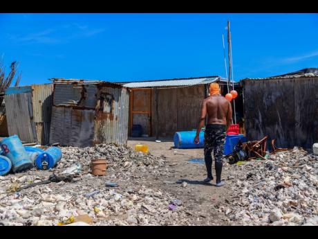 Credit: Antoine Lodge A man walks towards the houses on the garbage-infested Pedro Cays.