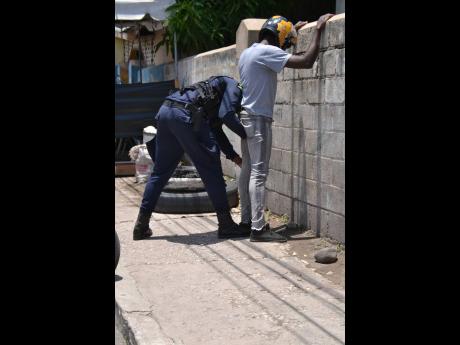 Credit: FILE A member of the security forces searches a man at a checkpoint along West Avenue in Greenwich Town.