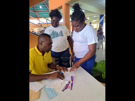 A volunteer at the Old Harbour Road Church of Prophecy back-to-school fair signs forms for attendees.