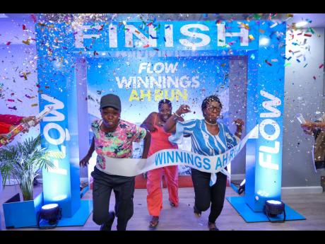 Grand prize winners in Flow’s ‘Winnings ah Run’ summer campaign (from left) Jasmine Ohara, Audrey Pink, and Donett Tucker race to the finish line during a reception at Flow’s corporate office in Kingston last Thursday. 