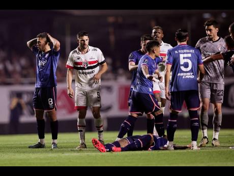 Juan Izquierdo of Uruguay’s Nacional (bottom) lies on the pitch after collapsing during a Copa Libertadores soccer game against Brazil’s Sao Paulo at Morumbi stadium in Sao Paulo, on Thursday, August 22.