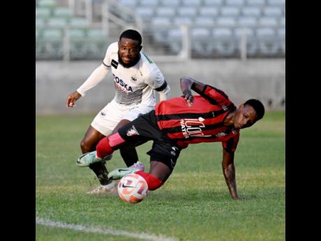 File photo shows Arnett Gardens’ Warner Brown falling after a tackle from Cavalier Soccer Club defender Gadail Irving during a Jamaica Premier League football match at Sabina Park on Sunday, January 7, 2023. Brown scored a double on Sunday in Arnett’s 3-0 win over Dunbeholden. 